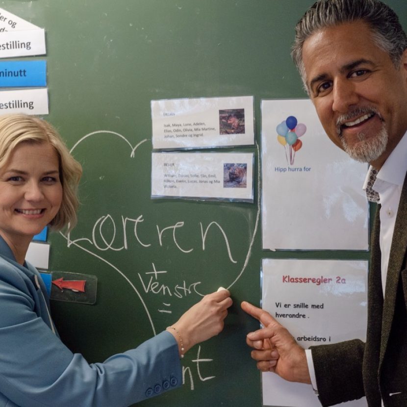 Guri og Abid peker på en tavle i et klasserom med et hjerte hvor det ser skrevet "Læreren + Venstre = Sant"