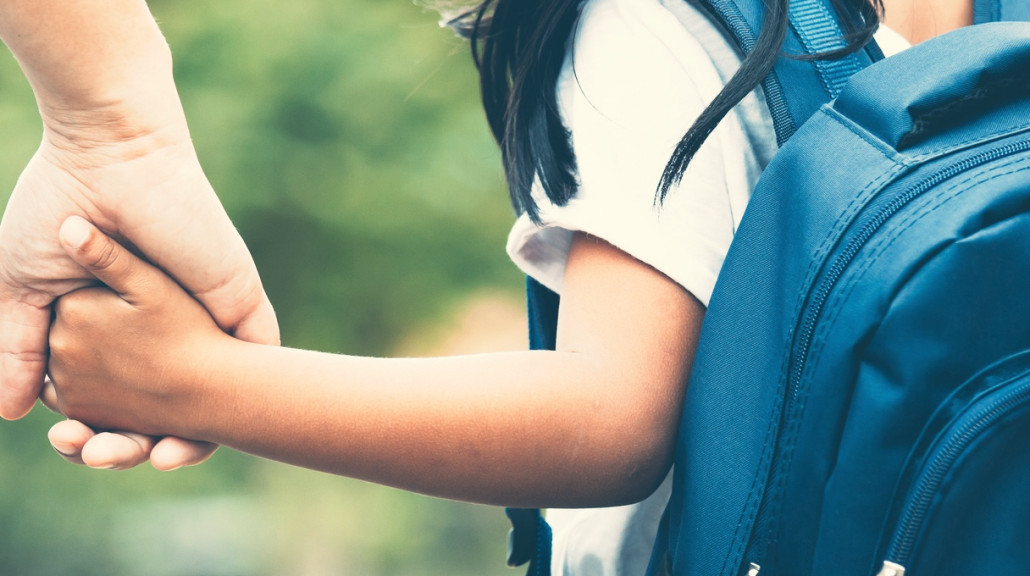 Skolejente på vei til skolen. holder en forelder i hånden.