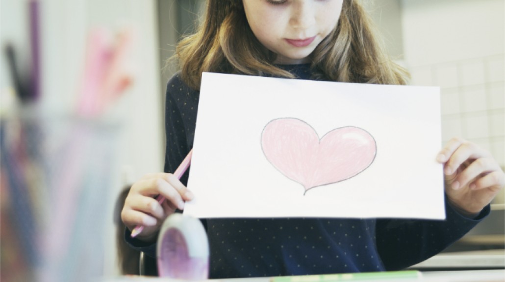 Skolejente som holder opp en tegning av et hjerte