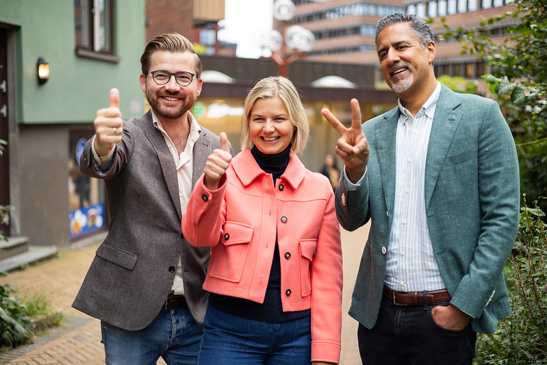 Foto av ledertrioen i Venstre som smiler, ser mot noen og viser tommel opp og V-tegn